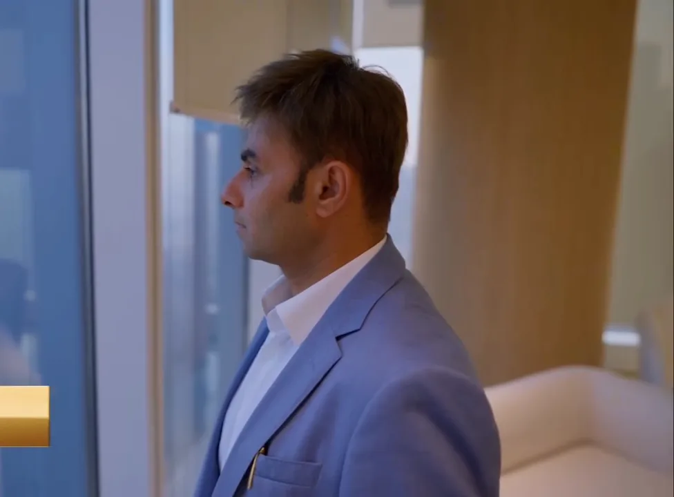 Maqsood Muhammed in a light blue suit by an office window